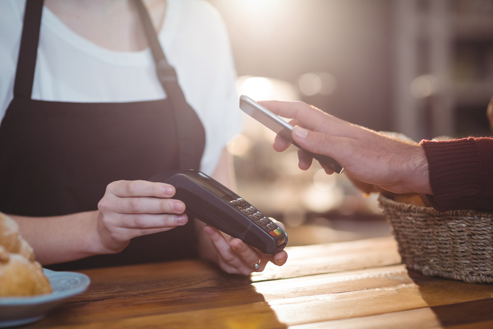 Customer paying bill through smartphone using NFC technology in cafe Customer paying bill through smartphone using NFC technology in cafe